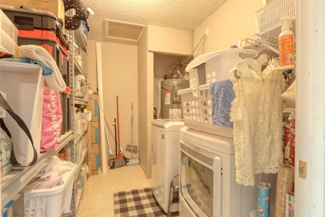 Laundry room featuring water heater, washer and clothes dryer, a textured ceiling, and attic access | Image 26