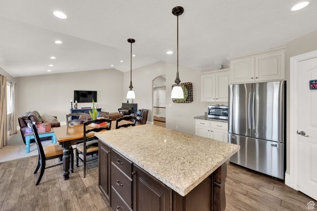 Kitchen with appliances with stainless steel finishes, vaulted ceiling, arched walkways, light wood-type flooring, and open floor plan | Image 8