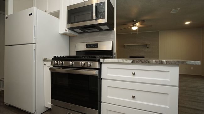 The kitchen opens to the family room. It features a stainless steel gas range and microwave. The refrigerator is included | Image 9
