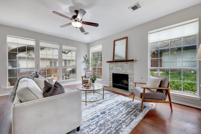 Living area with healthy amount of natural light, a ceiling fan, wood finished floors, and a stone fireplace | Image 10