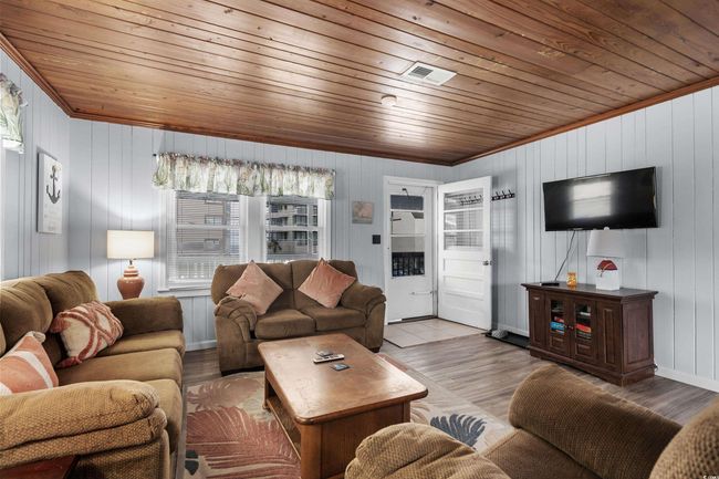 Living room featuring wooden ceiling, healthy amount of natural light, ornamental molding, wood finished floors, and wood walls | Image 17