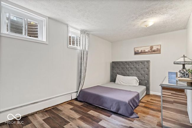 bedroom with baseboard heating, wood finished floors, and a textured ceiling | Image 25