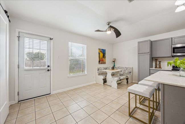 Kitchen with gray cabinets, stainless steel microwave, a ceiling fan, light tile floors, and backsplash | Image 11