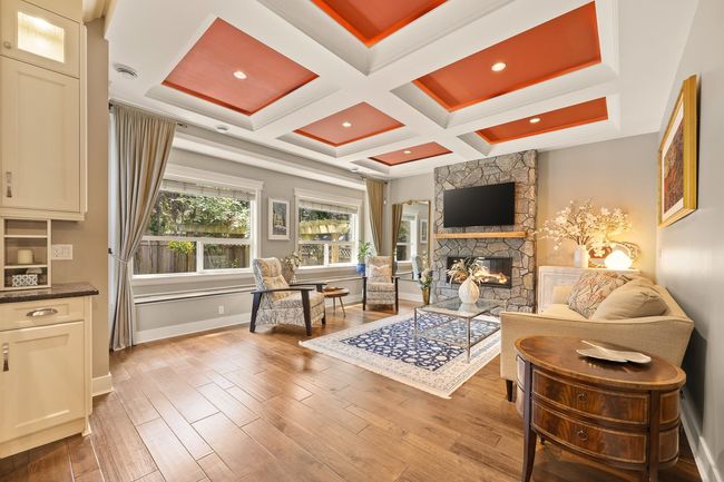 Living area with a fireplace, wood finished floors, coffered ceiling, and beam ceiling | Image 5