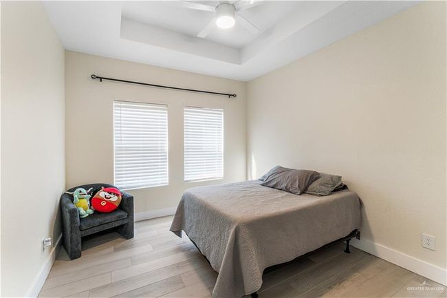 Bedroom featuring a tray ceiling, ceiling fan, and light hardwood / wood-style floors | Image 21
