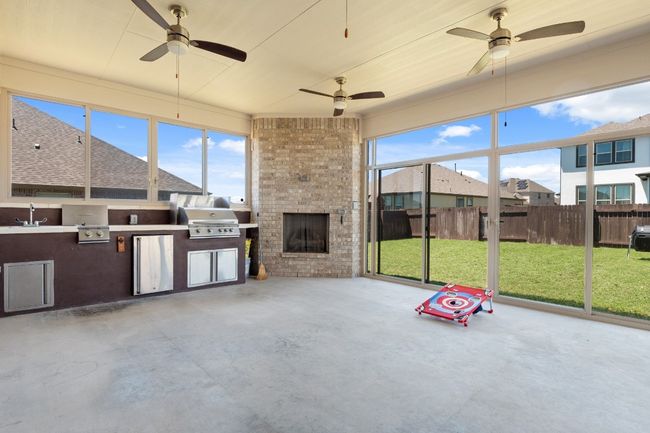 Unfurnished sunroom featuring ceiling fan, a wealth of natural light, and exterior kitchen | Image 32