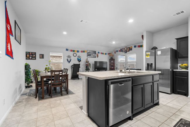 Kitchen with light countertops, a sink, visible vents, a kitchen island with sink, and appliances with stainless steel finishes | Image 11