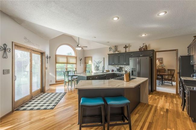 Kitchen featuring a sink, a breakfast bar, a textured ceiling, vaulted ceiling, and light wood-style flooring | Image 24