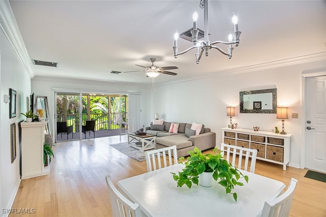 Dining room featuring crown molding, light wood finished floors, a chandelier, and a ceiling fan | Image 10