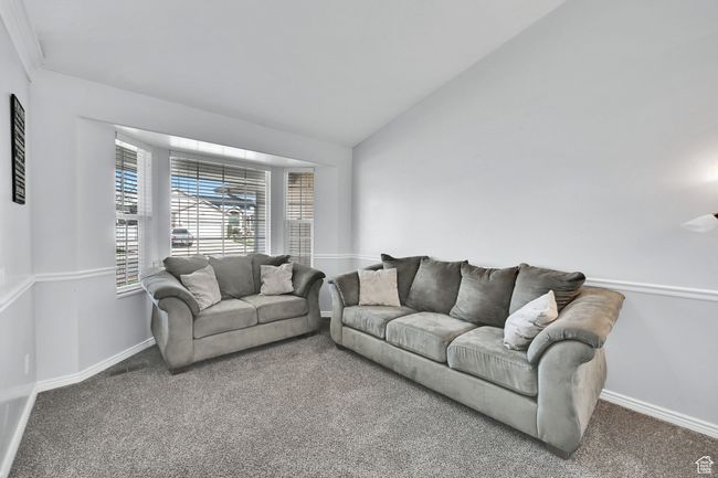 Carpeted living room with baseboards and lofted ceiling | Image 6