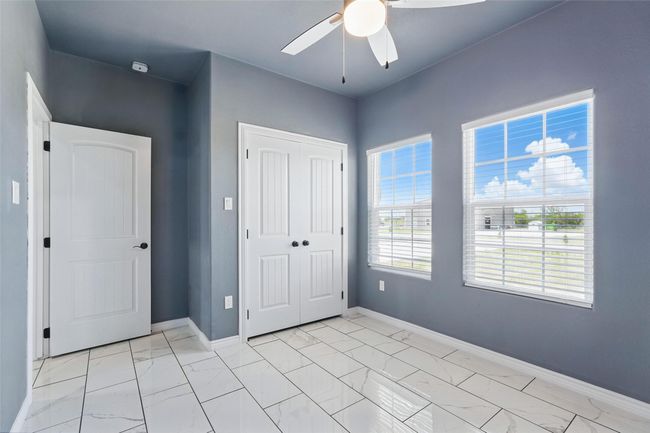 Unfurnished bedroom with a closet, tile finish floor, baseboards, and a ceiling fan | Image 18