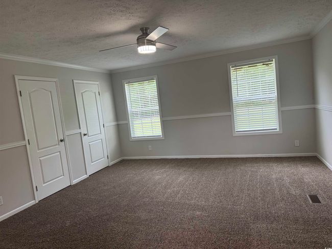 Carpeted empty room with ceiling fan, a textured ceiling, and ornamental molding | Image 18