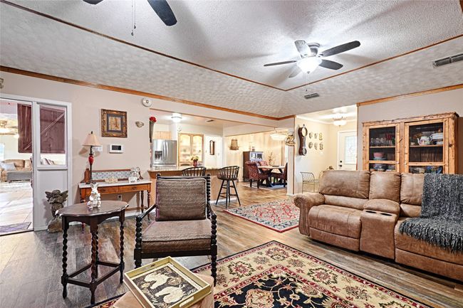 Living room with hardwood / wood-style floors, a textured ceiling, ceiling fan, and crown molding | Image 21