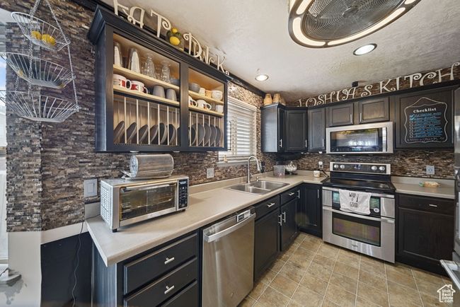 Kitchen with a toaster, stainless steel appliances, a sink, light countertops, and decorative backsplash | Image 8