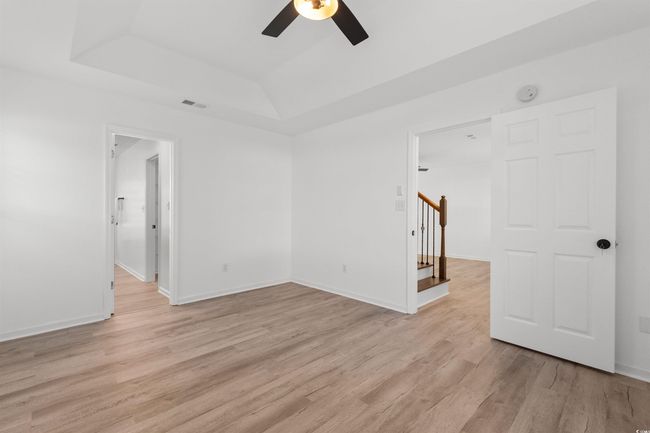 Unfurnished living room with light wood-style flooring, stairs, a chandelier, baseboards, and a ceiling fan | Image 11