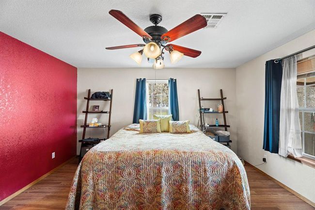 Bedroom with a ceiling fan, wood finished floors, a textured ceiling, baseboards, and visible vents | Image 26