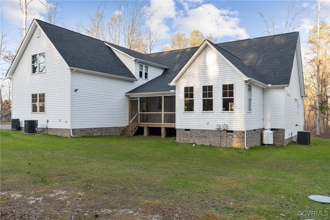 Rear view of property featuring central AC, a lawn, a sunroom, and a shingled roof | Image 46