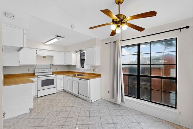 Kitchen with white appliances, a sink, a ceiling fan, light countertops, and white cabinets | Image 14
