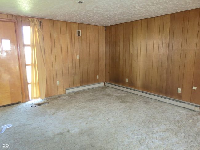 spare room with visible vents, wood walls, baseboard heating, carpet flooring, and a textured ceiling | Image 6