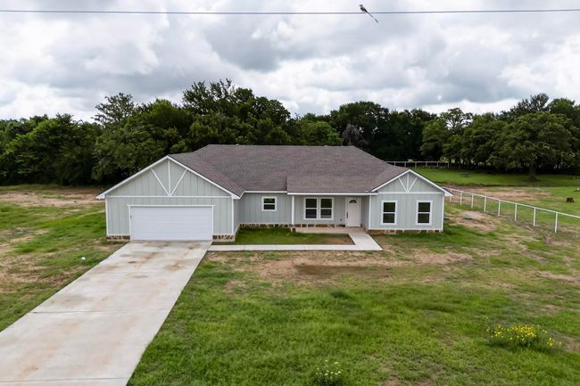 Ranch-style house with a shingled roof, concrete driveway, board and batten siding, and a garage | Image 8
