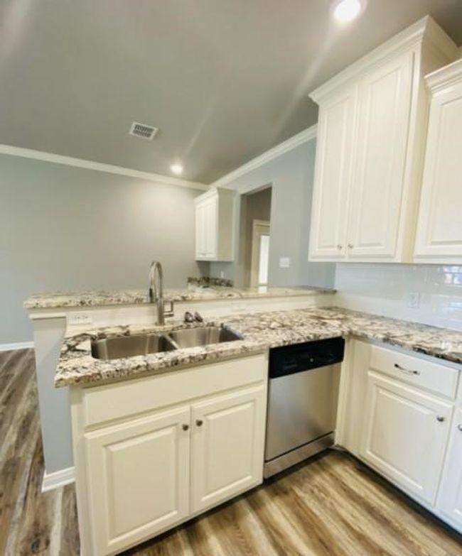 Kitchen with dishwasher, a sink, ornamental molding, wood finished floors, and white cabinets | Image 6