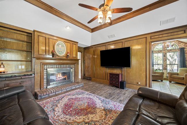Living room featuring visible vents, a high ceiling, a ceiling fan, a fireplace, and crown molding | Image 14