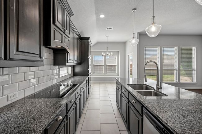 Kitchen featuring black electric cooktop, a sink, an inviting chandelier, light tile patterned floors, and decorative backsplash | Image 21