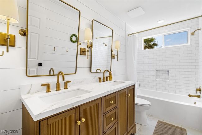 Full bathroom featuring double vanity, shower / bath combo with shower curtain, toilet, and a sink | Image 31
