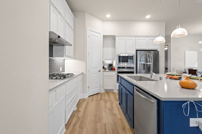 Kitchen with blue cabinetry, light wood-style floors, under cabinet range hood, appliances with stainless steel finishes, and white cabinetry | Image 7