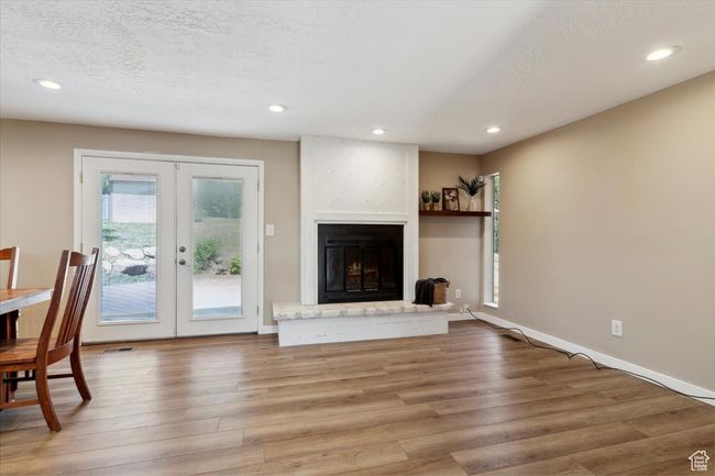 Living room with french doors, wood LVP floors, recessed lighting, a fireplace, and a floating shelf. | Image 5