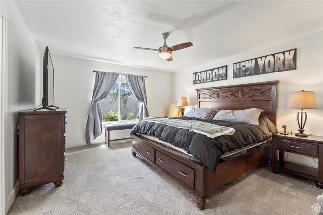 Bedroom featuring light colored carpet, a ceiling fan, baseboards, and a textured ceiling | Image 15