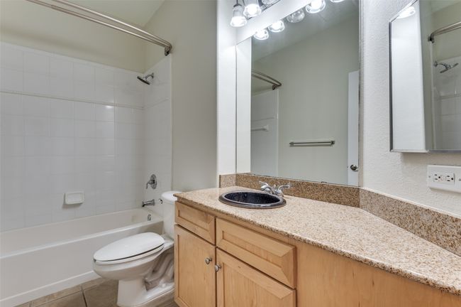 The hallway bath, conveniently located just across from the guest bedroom, features a sleek granite countertop, a stylish vessel sink that adds a unique touch, and a versatile shower/bath combination—perfect for guests or everyday use. | Image 34