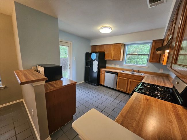 Kitchen with wood counters, stainless steel appliances, a sink, and visible vents | Image 14