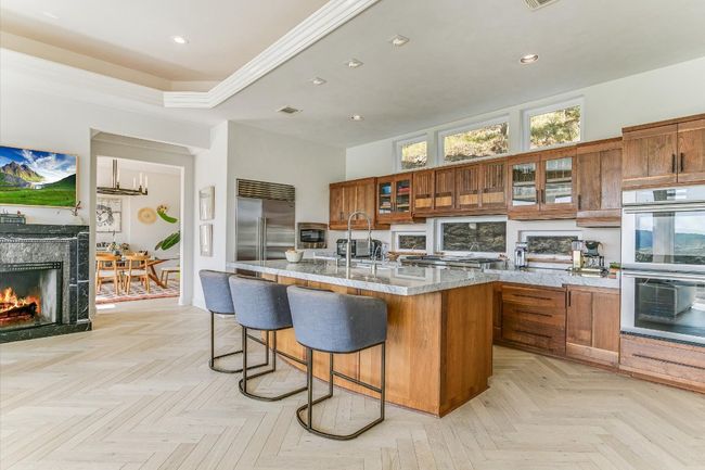 Kitchen featuring stainless steel appliances, brown cabinets, a breakfast bar area, a center island with sink, and recessed lighting | Image 12