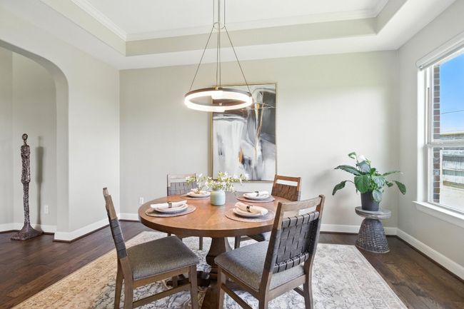 Dining area featuring a tray ceiling, wood finished floors, plenty of natural light, and crown molding | Image 9