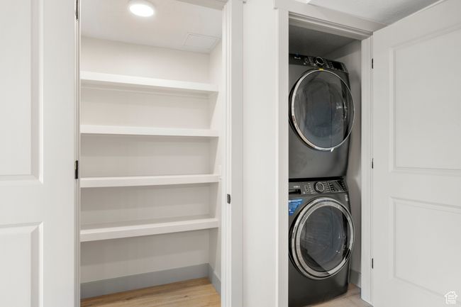 Laundry area with stacked washing machine and dryer and wood finished floors | Image 17