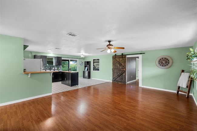 Unfurnished living room with a barn door, light wood finished floors, and ceiling fan | Image 4