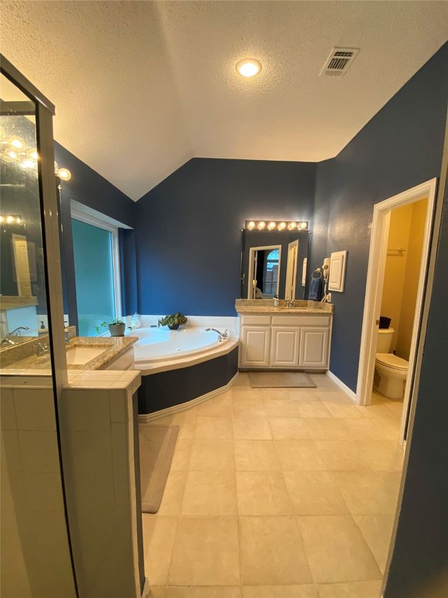 Bathroom with a bath, a textured ceiling, visible vents, vaulted ceiling, and vanity | Image 24
