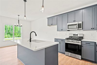 Kitchen with a kitchen island with sink, light hardwood / wood-style flooring, stainless steel appliances, and sink | Image 3