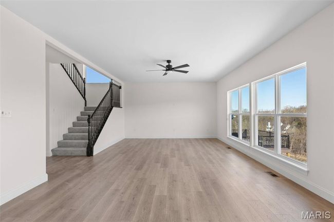 Unfurnished living room with ceiling fan, light wood finished floors, and stairway | Image 21