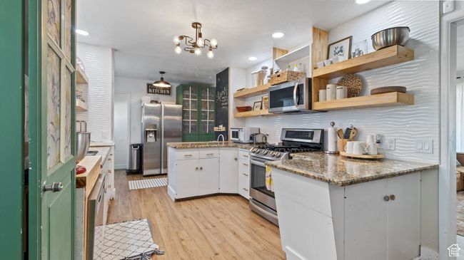 Kitchen featuring open shelves, backsplash, light wood-type flooring, appliances with stainless steel finishes, and white cabinetry | Image 8
