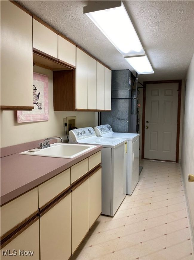Washroom featuring independent washer and dryer, cabinet space, a textured ceiling, and light floors | Image 24