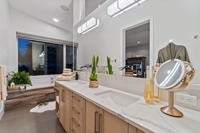 Bathroom featuring double vanity, a bath, tile patterned flooring, and lofted ceiling | Image 11
