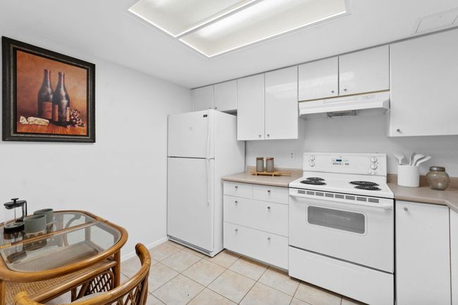 Kitchen featuring under cabinet range hood, white appliances, light countertops, and white cabinets | Image 7