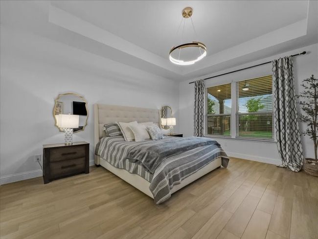 Bedroom featuring a raised ceiling, light wood-style flooring, and baseboards | Image 8