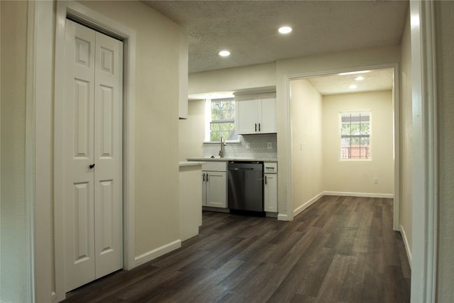 Kitchen with backsplash, dishwasher, dark wood-type flooring, and white cabinets | Image 6