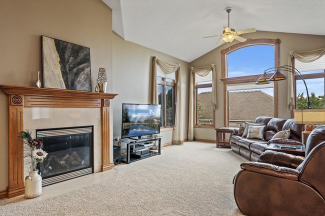 Expansive windows create a grand feel to the main level living room. The convenience of a cozy gas fireplace & mantle top it off for the ideal place to lounge & relax | Image 14