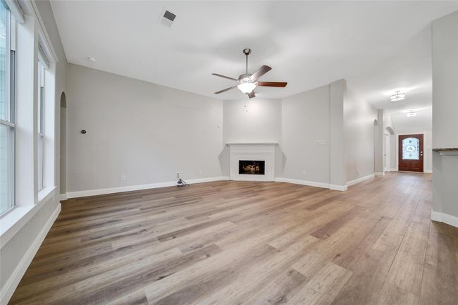 A corner gas log fireplace anchors the space. The luxury vinyl plank flooring that runs throughout the main living areas and primary bedroom provides seamless transitions from room to room. | Image 8