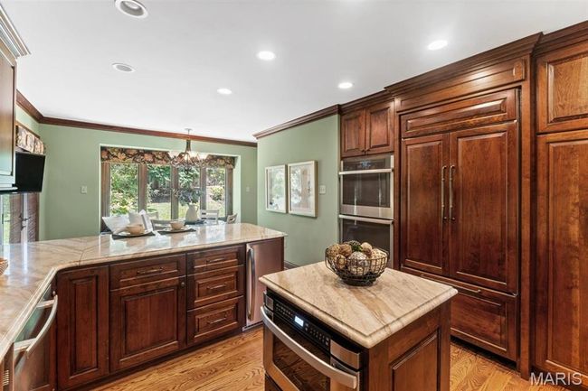 Kitchen featuring ornamental molding, a chandelier, stainless steel double oven, recessed lighting, and fridge | Image 21