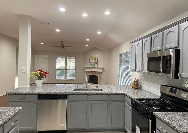 Kitchen featuring stainless steel appliances, gray cabinets, a peninsula, recessed lighting, and lofted ceiling | Image 8